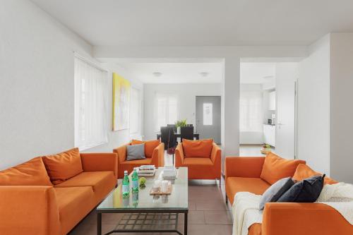 a living room with orange couches and a table at Swiss Star Oerlikon Lodge - Self Check-In in Zürich