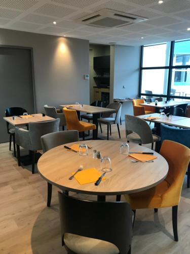 a dining room with wooden tables and chairs at The Originals City, Hôtel Hélios, Roanne Nord in Mably