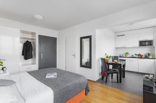 a white bedroom with a bed and a kitchen at Swiss Star Oerlikon Lodge - Self Check-In in Zürich