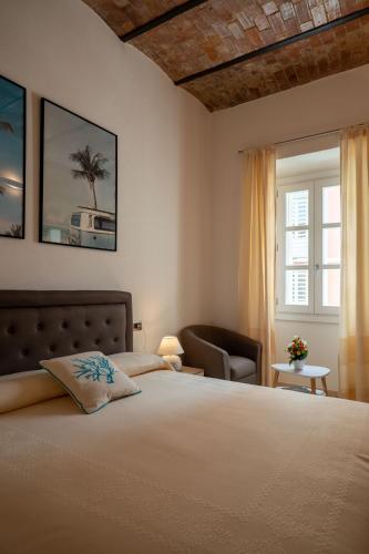 a bedroom with a bed and a chair and a window at Corso Umberto Rooms in Olbia