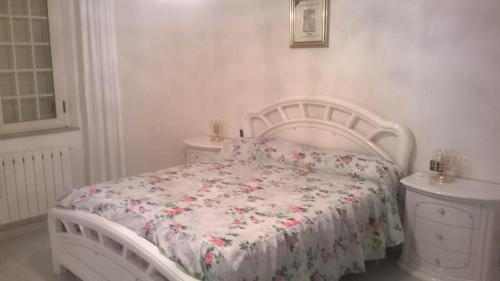 a white bedroom with a white bed with a floral bedspread at CASA ELEGANTE in Martinsicuro