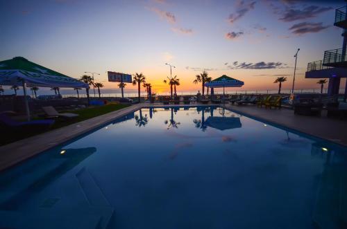 a large swimming pool with a sunset in the background at Batumi Palm Hotel in Batumi