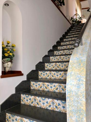 a staircase with tile floors and a vase with flowers at Farfalle E Gabbiani in Tramonti