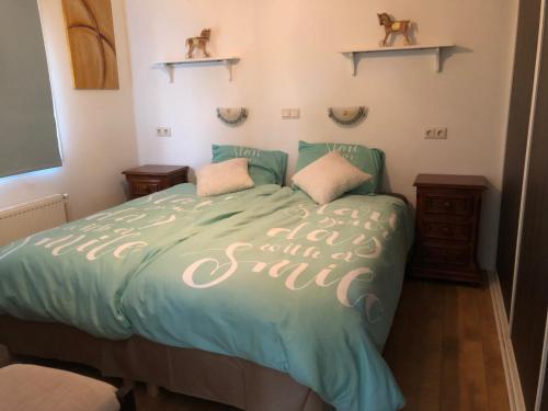 a bedroom with a bed with a green comforter with the words had at bungalow Onder de iep in Ermelo