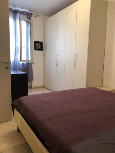 um quarto com uma cama, armários brancos e uma janela. em Casa lux em Rimini