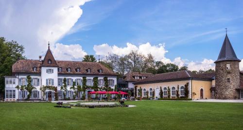 ein großes weißes Gebäude mit einem Turm und einem grünen Hof in der Unterkunft Château de Bossey in Bogis-Bossey