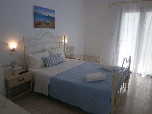 a bedroom with a large bed with a blue blanket at Hotel Flisvos in Megalochori