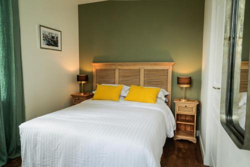 a bedroom with a white bed with two yellow pillows at LE PATIO DE CLARA in Le Touquet-Paris-Plage