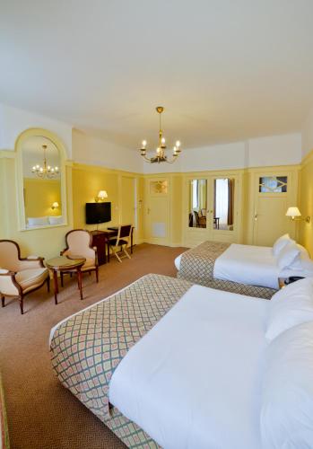 a hotel room with two beds and a living room at Hôtel Mercure Bayonne Centre Le Grand Hotel in Bayonne