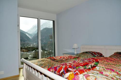 a bedroom with a bed and a large window at Chasa Miramunt 9 in Scuol