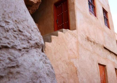 a building with a red door on the side of it at Hissen Al-Misfah in Misfāh