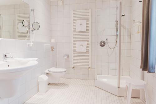 a white bathroom with a toilet and a sink at Ringhotel Teutoburger Wald in Tecklenburg