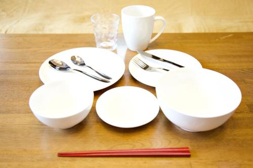 a group of white plates and silverware on a table at Gunma House in Maebashi