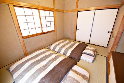 two beds in a small room with two windows at Gunma House in Maebashi