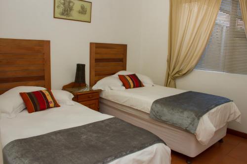 a bedroom with two beds and a window at Helderzicht Self-Catering in Brackenfell