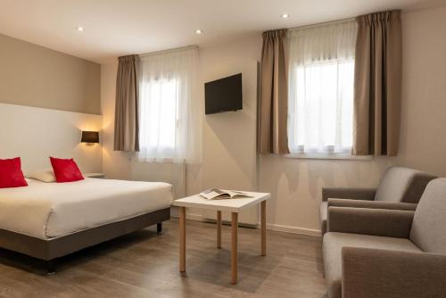 Pokój hotelowy z łóżkiem i krzesłem w obiekcie Hotel The Originals Bernay Acropole w mieście Bernay