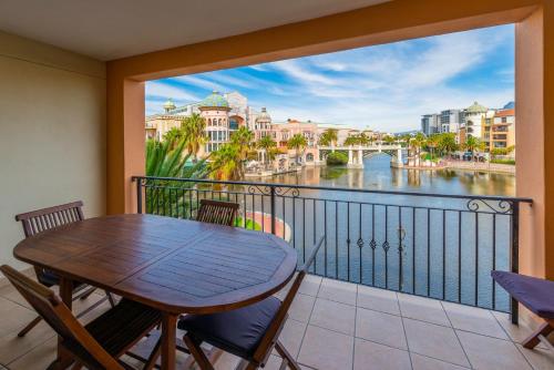 balcón con mesa, sillas y vistas al río en Majorca Self-Catering Apartments en Ciudad del Cabo