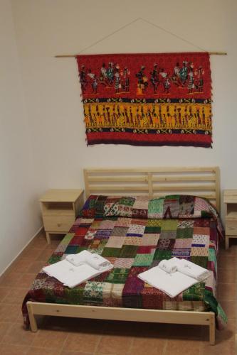 a bedroom with a bed with a quilt on it at Beteyà Hostel Don Bosco in Catania