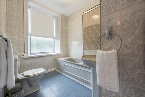 a bathroom with a sink and a tub and a toilet at The Imperial Crown Hotel in Halifax