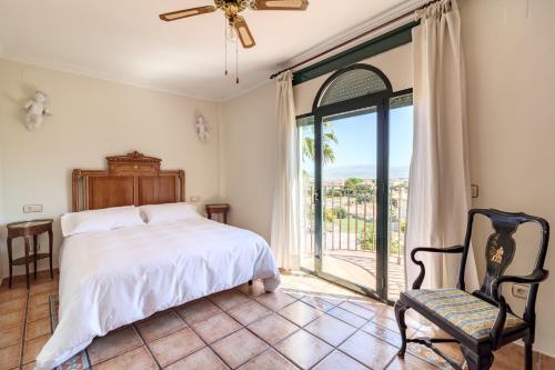 a bedroom with a bed and a window and a chair at Villa La Piedad in Otura