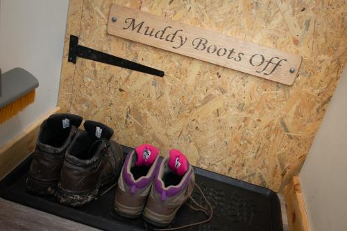 a pair of shoes and a sign that reads muddy boots off at Lochanside in Struan