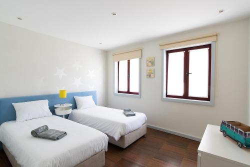 two beds in a room with two windows at Porto Gaia City House by MP in Vila Nova de Gaia