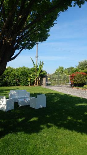 two white chairs sitting in the grass under a tree at B&B Villa dei Sogni in Eboli