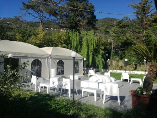 une tente avec des tables et des chaises blanches dans un jardin dans l'établissement Costa Morroni, à Levanto