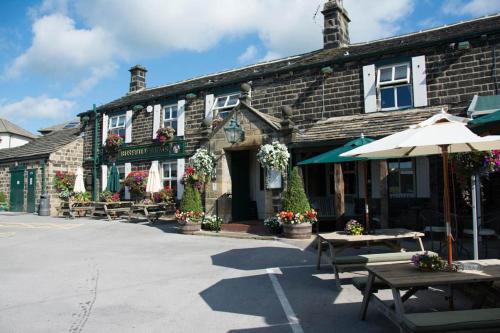 a building with tables and umbrellas in front of it at Busfeild Arms in Keighley