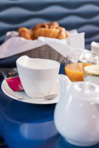 una mesa con un plato de comida y un tazón de pan en BRIT HOTEL PRIVILEGE LISIEUX - La Villa des Arts, en Lisieux
