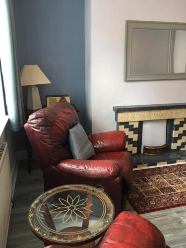 a living room with a red leather chair and a table at Lily's in Manorhamilton