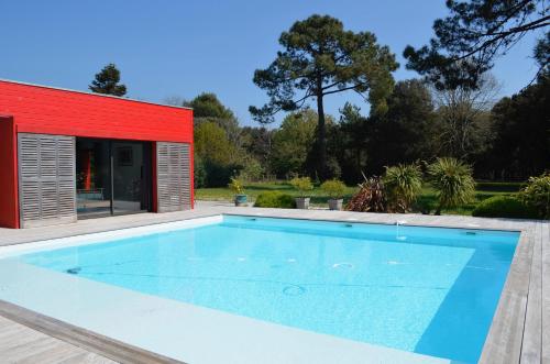 una piscina en una casa con un edificio rojo en Les Naiades, en Dolus d'Oléron