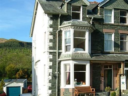 a large brick house with a bench in front of it at Craglands Guest House in Keswick