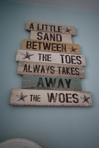 a sign that says a little sand between the toes always takesavis takesaway at Weymouth Vegan B&B in Weymouth