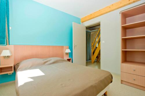 une chambre avec un lit et un mur bleu dans l'établissement Résidence Goélia Les Cottages du Lac, à Coly