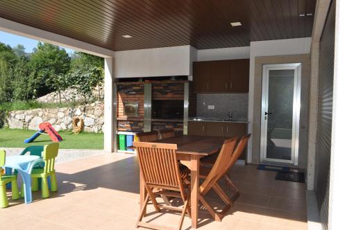 a kitchen with a wooden table and chairs on a patio at Casa da Quinta do Sóto in Terras de Bouro