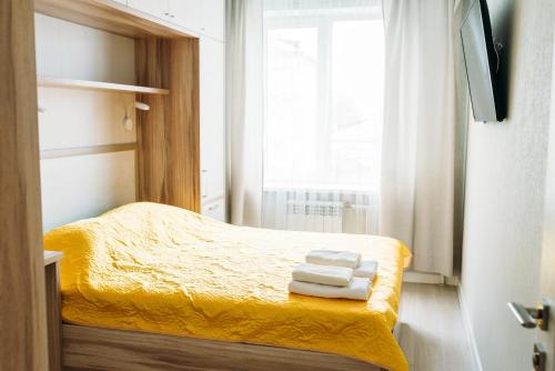 a small bedroom with a yellow bed with towels on it at Роскошные апартаменты RentHome в центре in Kemerovo