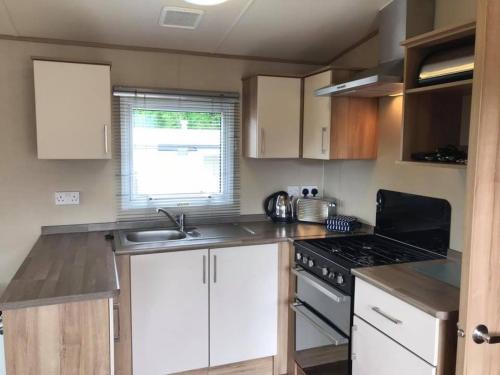 a kitchen with white cabinets and a stove top oven at Luxury Holiday Caravan Home in Newquay