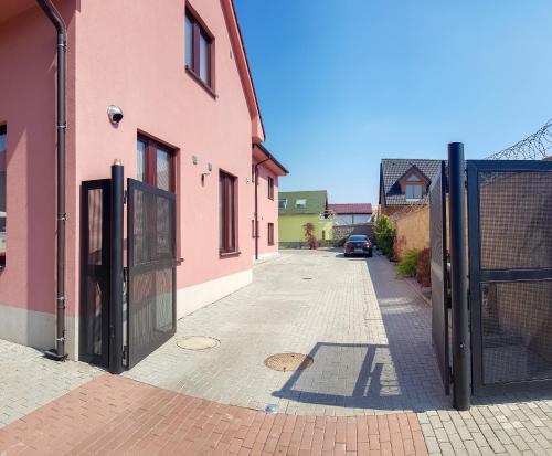 an empty street with a pink building and a gate at Apartment De Luna in Prague