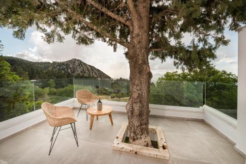 a balcony with a tree and two chairs and a table at Forest View Villas in Lagoúdi Zía