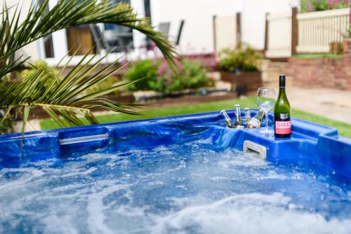a hot tub with a bottle of wine and glasses at City Retreat, Spacious 4 Bed House, Games Room, Parking, Hot Tub & BBQ in Cardiff