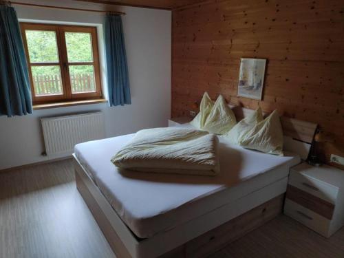 1 dormitorio con 1 cama grande con sábanas y almohadas blancas en Ferienwohnung Waldblick en Scheffau am Wilden Kaiser