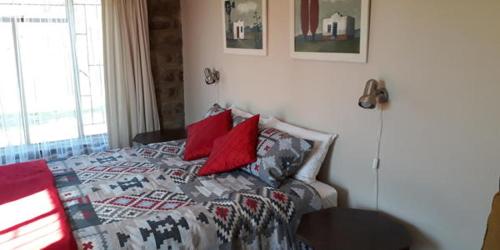 een slaapkamer met een bed met rode kussens erop bij MacFarlanes in Harrismith