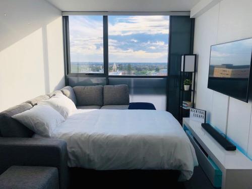 a bedroom with a bed and a couch and a large window at Central Escape @ Adelaide CBD in Adelaide