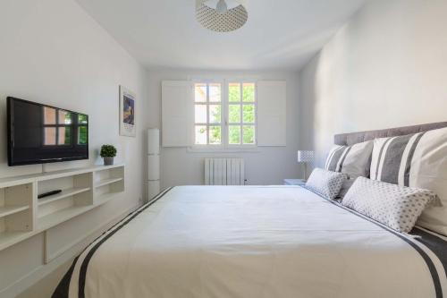 a white bedroom with a large bed and a television at Appartement cathédrale au calme in Aix-en-Provence