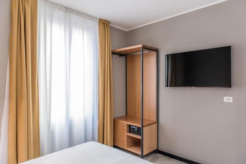 a bedroom with a bed and a tv and a curtain at APARTHOTEL CASA MIA in Milan
