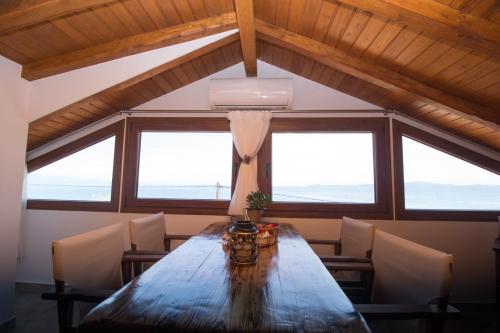 a dining room with a wooden table and windows at Golden Attic in Nea Roda