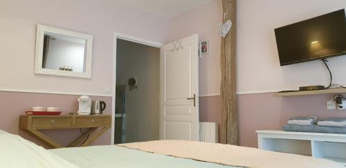 1 dormitorio con 1 cama y TV en la pared en Au Clos du Coteau, Chambres d'Hôtes en Crotelles
