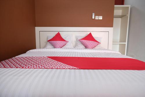 a large white bed with red pillows on it at SUPER OYO 811 Mars Kost Syariah in Jambi
