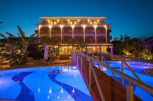 a hotel with a swimming pool in front of a building at Paradise Lost Hotel-Apartments in Tolo